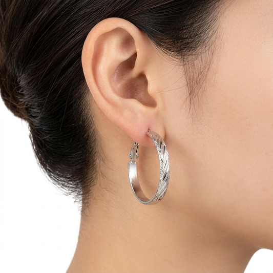 Srebrny fakturowany kolczyk kółko na uchu modelki na białym tle