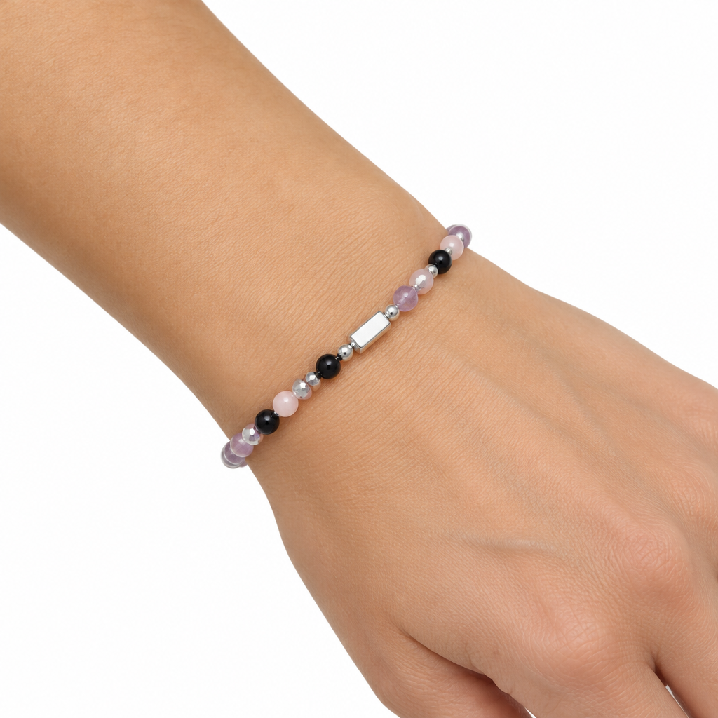 Bransoletka z fioletowymi rozowymi i czarnymi koralikami na nadgarstku modelki, biale tlo